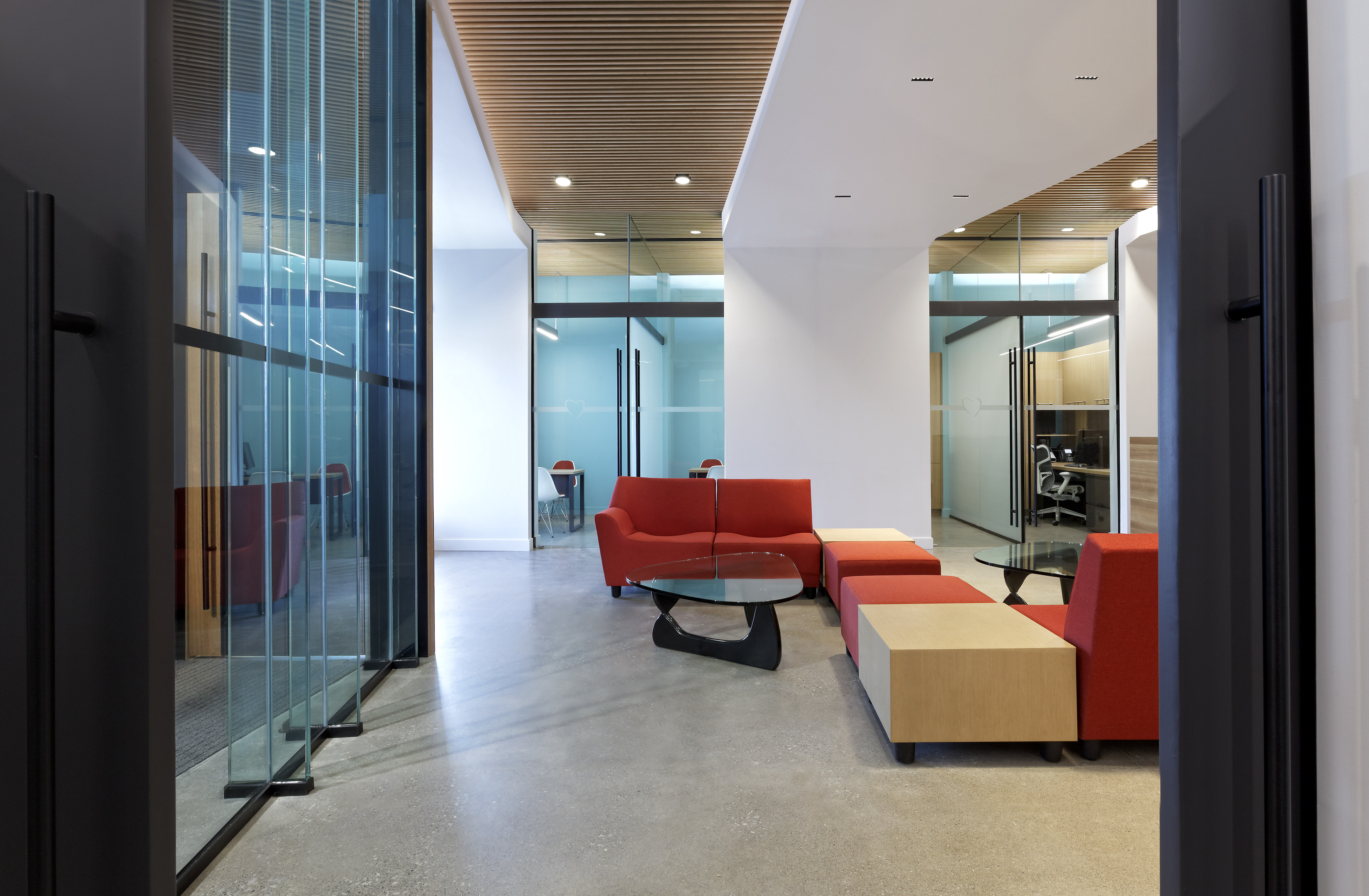 Waiting room with red sofas and warm wood ceiling
